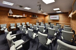 A conference room with rows of chairs, a projector screen, and wooden panel walls. - Aplend Kukucka Mountain Hotel & Residences (Vysoké Tatry)
