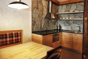 Eine kleine Küche mit Steinrückwand, Holzschränken und einer schwarzen Arbeitsplatte.