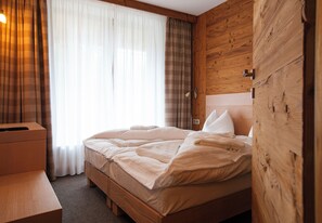 Una cama bien hecha con cabecera de madera, una mesita de noche y una ventana con cortinas.