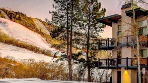 Ein Hotel mit Skipiste im Hintergrund, einem Balkon mit Geländer und verschneitem Gelände.