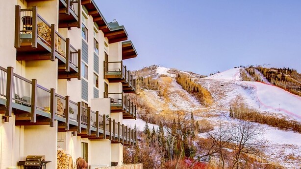 Ein mehrstöckiges Hotel mit Balkonen und einem Ski-Hang im Hintergrund.