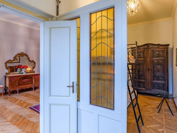 Een kamer met een witte deur, een houten kast en een kroonluchter.
