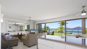 A modern living room with a large island, a sofa set, and a dining area with a view of the sea. - Noosa Shores (Noosa Heads)