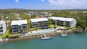A modern hotel with a pool, located near a body of water with boats. - Noosa Shores (Noosa Heads)
