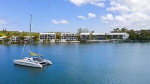 A marina with a sailboat docked near modern buildings with multiple floors and balconies. - Noosa Shores (Noosa Heads)