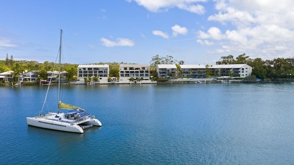 A marina with a sailboat docked near modern buildings with multiple floors and balconies.