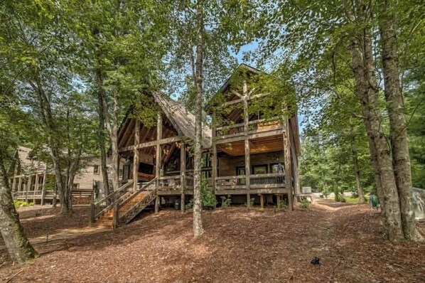 Eine Holzhütte mit einer Treppe, die zu einem Balkon führt, umgeben von Bäumen.
