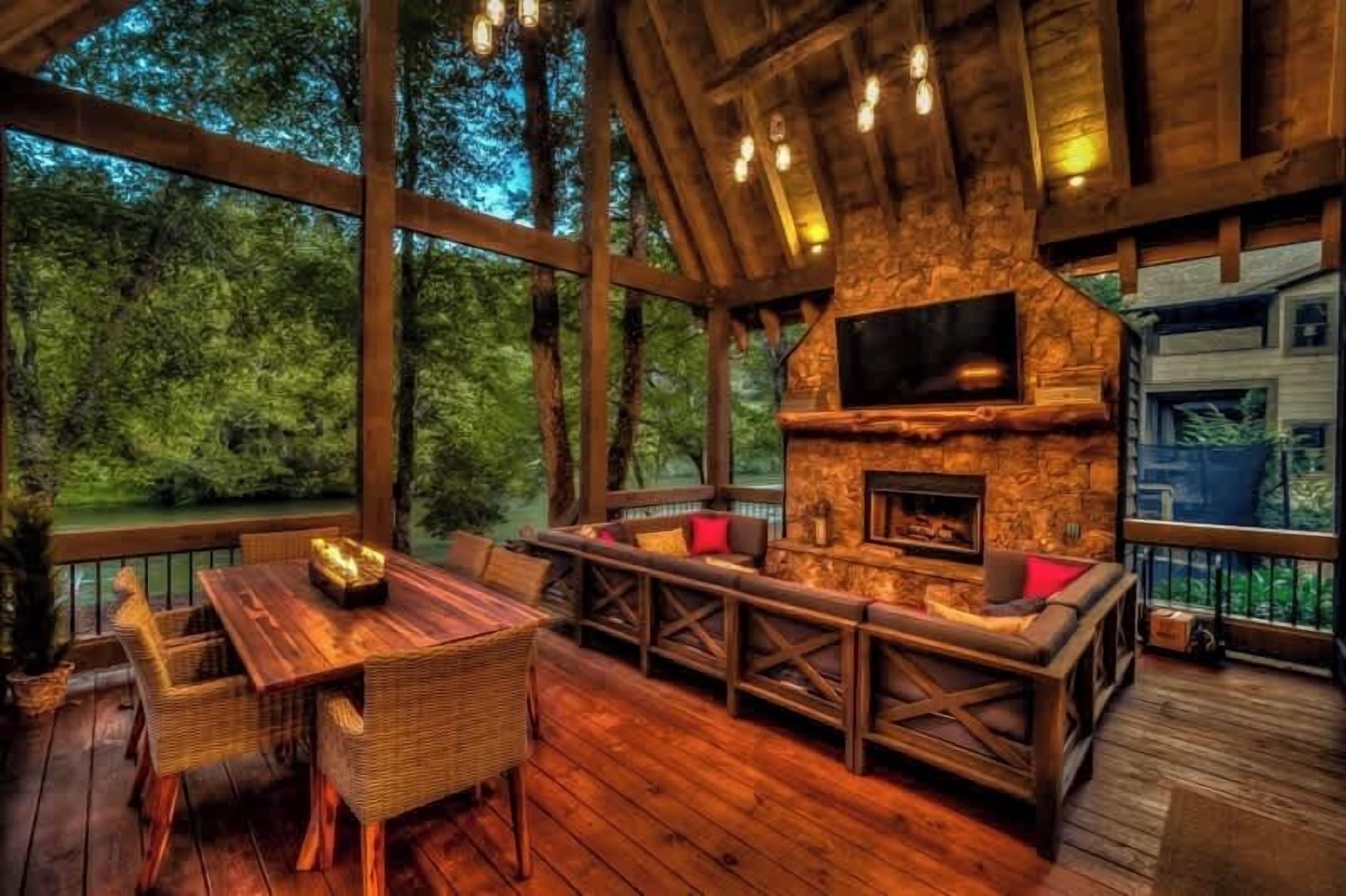 Une terrasse extérieure en bois avec une cheminée en pierre, des sièges et un téléviseur.
