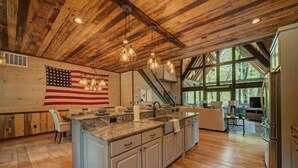 Una cocina amplia con una isla grande, techo de madera y un ventanal que proporciona luz natural.