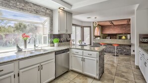 A modern kitchen with white cabinets, a granite countertop, and a brick backsplash. - Extraordinary Private Pool/Spa Villa w/man cave (Henderson)