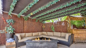 A covered outdoor seating area with a fire pit, cushioned seating, and decorative plants. - Extraordinary Private Pool/Spa Villa w/man cave (Henderson)