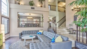 A spacious living area with a large sectional sofa, a round coffee table, and a staircase leading to an upper level. - Extraordinary Private Pool/Spa Villa w/man cave (Henderson)