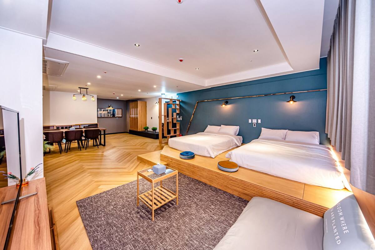 Een moderne hotelkamer met twee bedden, een zithoek en een kitchenette.