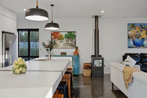 A modern kitchen with a central island, a built-in stove, and a dining area with benches. - Executive family house, private with stunning rural views close to Lake Rotoura (Rotorua)