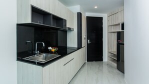 Cozinha moderna com armários de madeira clara, bancada preta e pia de aço inoxidável.
