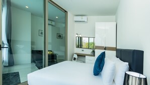Quarto de hotel moderno com uma cama grande, uma escrivaninha e uma porta de vidro que dá para uma varanda.