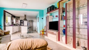 Un salon moderne avec un canapé, un téléviseur et une vitrine contenant des objets décoratifs.