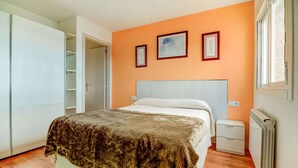 Une chambre à coucher avec un lit, une armoire, un radiateur et une fenêtre.