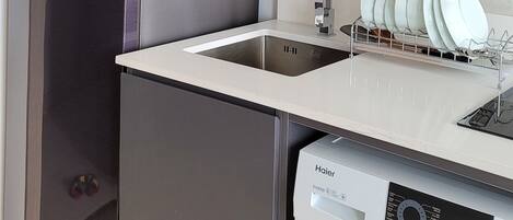 A compact kitchen with a refrigerator, microwave, sink, and dishwasher.