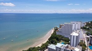 A coastal view with a beach, a large hotel, and boats on the water. - The Andromeda Condominium (Pattaya)