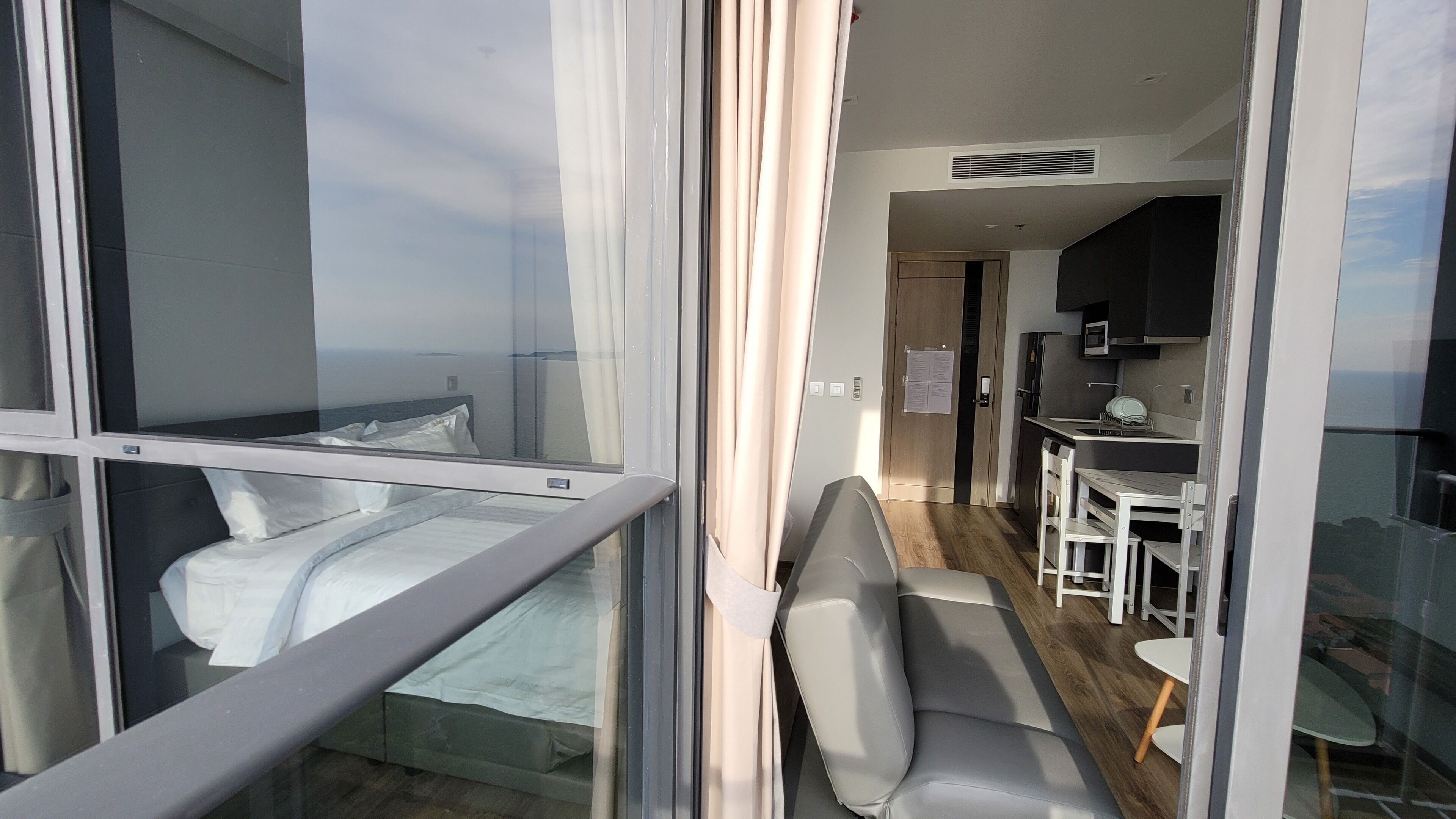 Una camera d'albergo moderna con una grande finestra, un letto, un divano e angolo cottura.