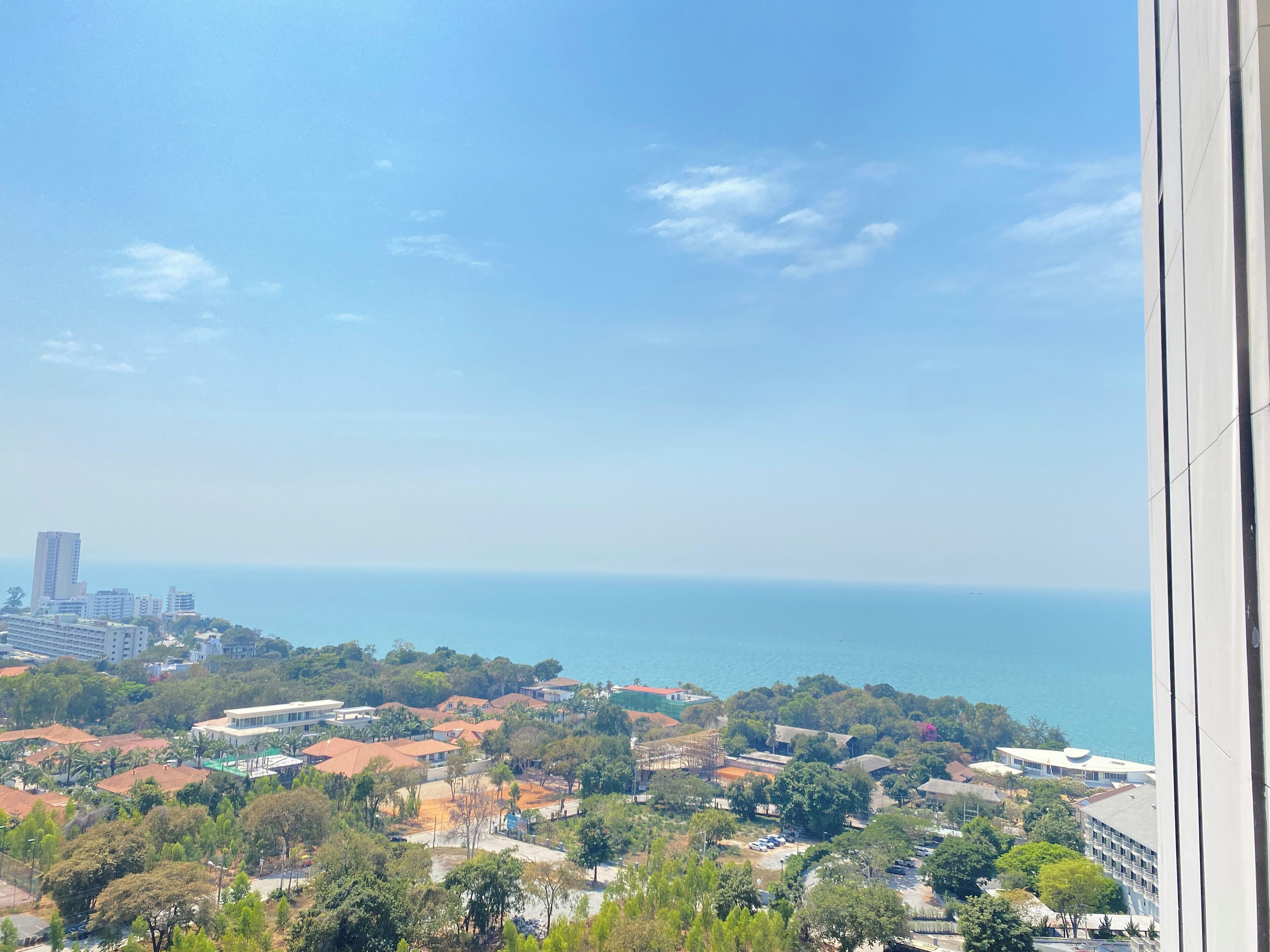 A coastal cityscape with buildings, trees, and a view of the sea.