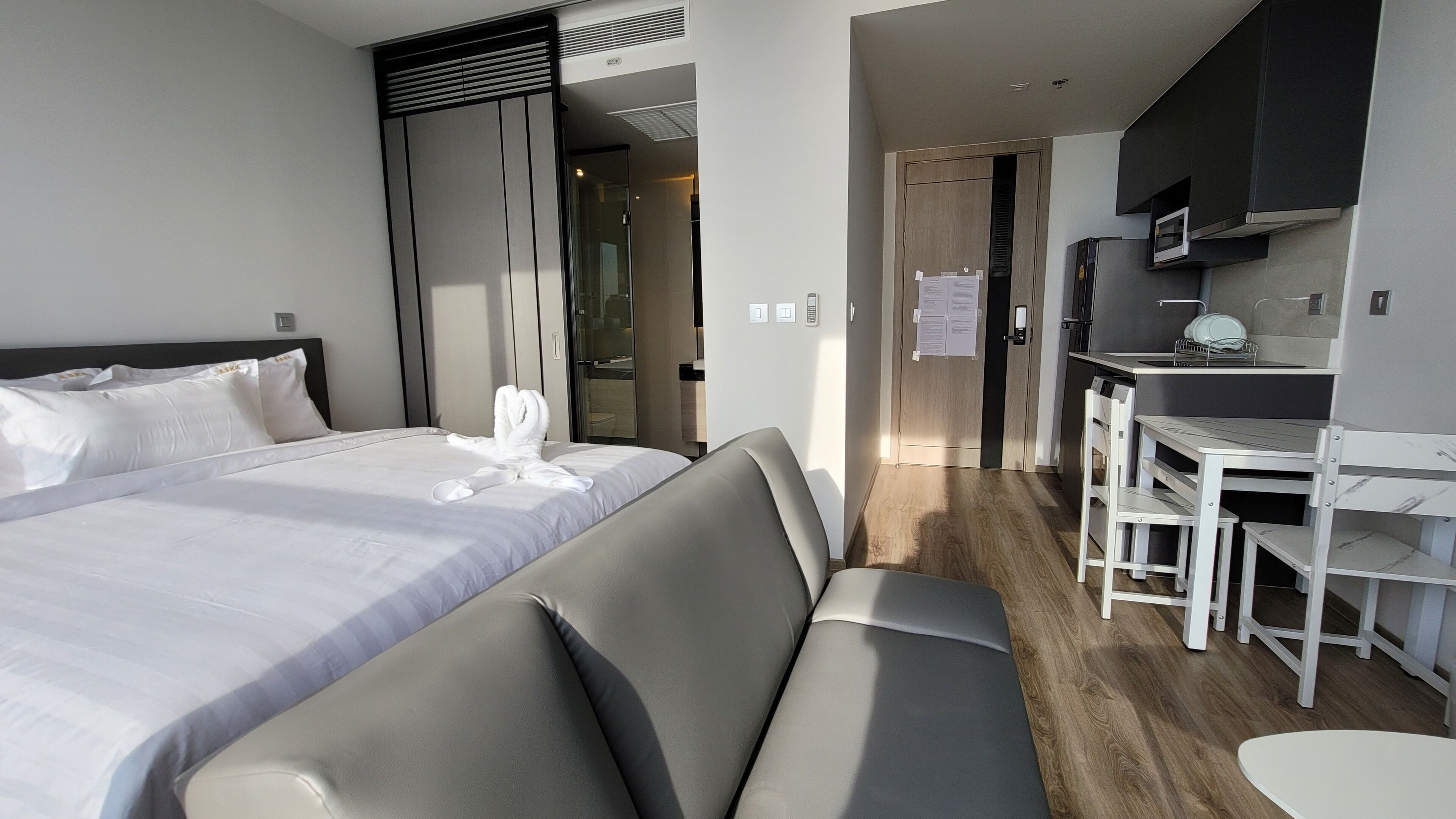 Hotellihuone, jossa on suuri sänky, sohva, pieni pöytä ja pieni keittiö.