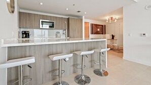 A modern kitchen with a central island, bar stools, and a dining area with a chandelier.