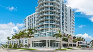 A modern multi-story hotel with a curved facade, large windows, and a central entrance. - Tiffany Ebony: 11th FL,Ocean-Canal views, Walk to Beach (Fort Lauderdale)
