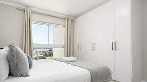Um quarto com uma cama grande, uma janela com cortinas e um guarda-roupa.