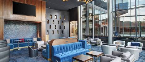 A modern lounge area with a blue sofa, armchairs, and a wooden accent wall.