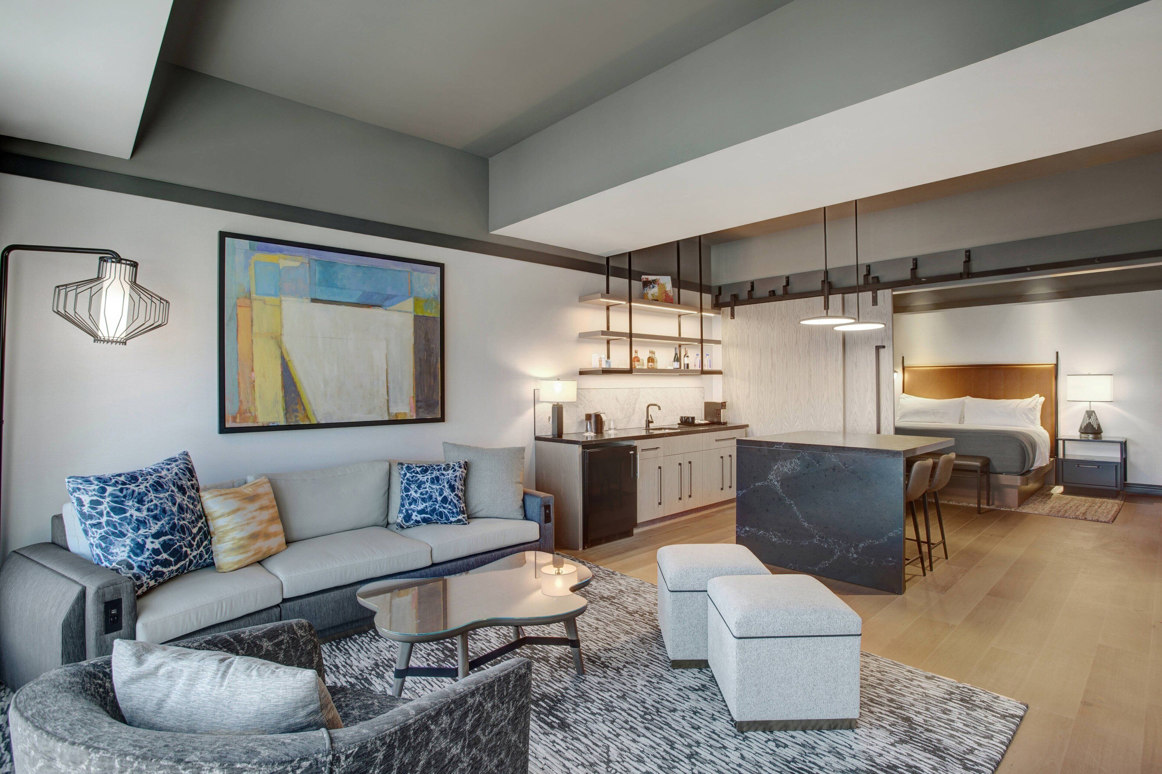 A modern apartment with a living area, kitchenette, and a bedroom.