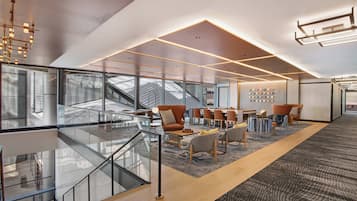 Un espacio de oficina moderno con paredes de vidrio, una escalera y mobiliario contemporáneo.