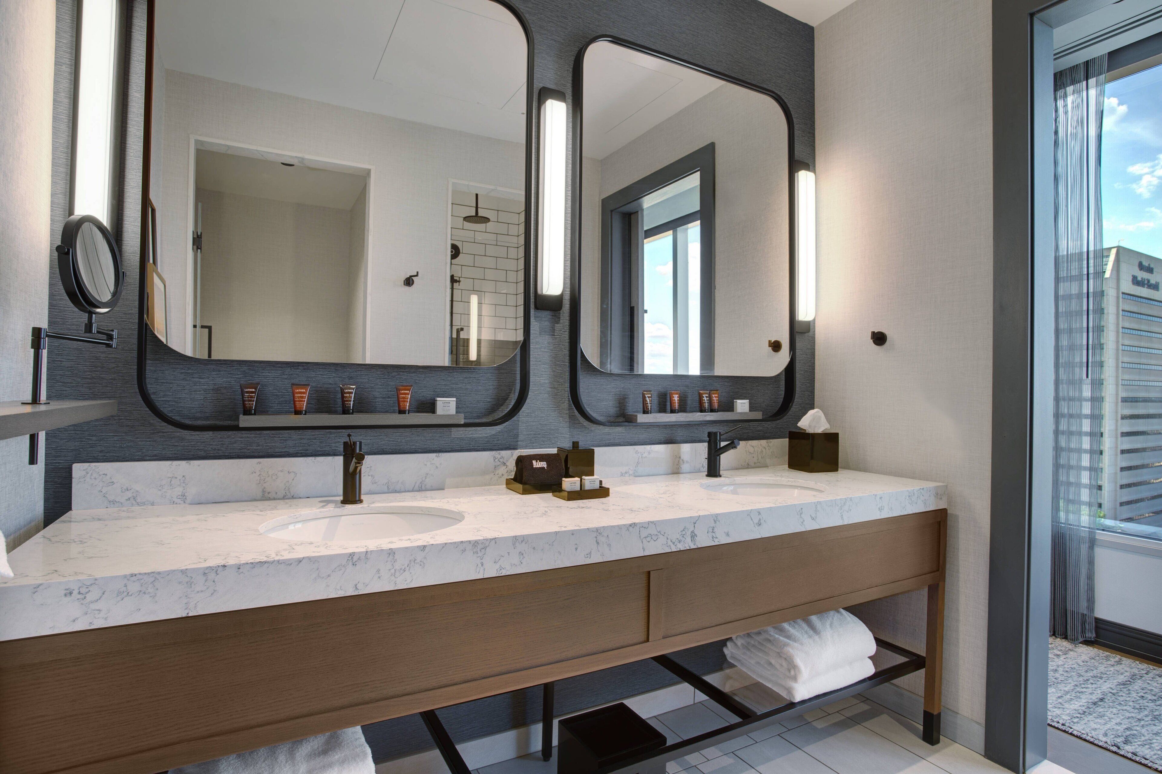 A modern bathroom with a large mirror, dual sinks, and a vanity with a towel rack.