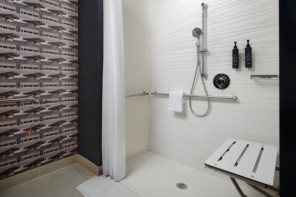 A modern bathroom with a shower, a towel rack, and two bottles of shampoo on the wall. - Aloft by Marriott Orlando at SeaWorld (Orlando)