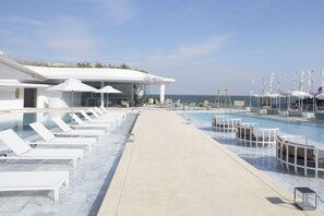 A poolside area with lounge chairs, umbrellas, and a clear view of the ocean. - VERSO Hua Hin - a Veranda Collection (Hua Hin)