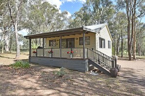 A small, single-story cabin with a porch and a staircase leading to the entrance.