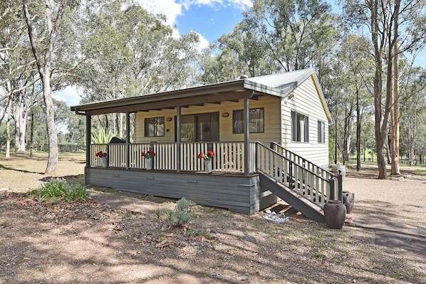 A small, single-story cabin with a porch and a staircase leading to the entrance.
