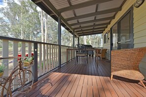 A wooden deck with a covered area, outdoor furniture, and a bicycle.
