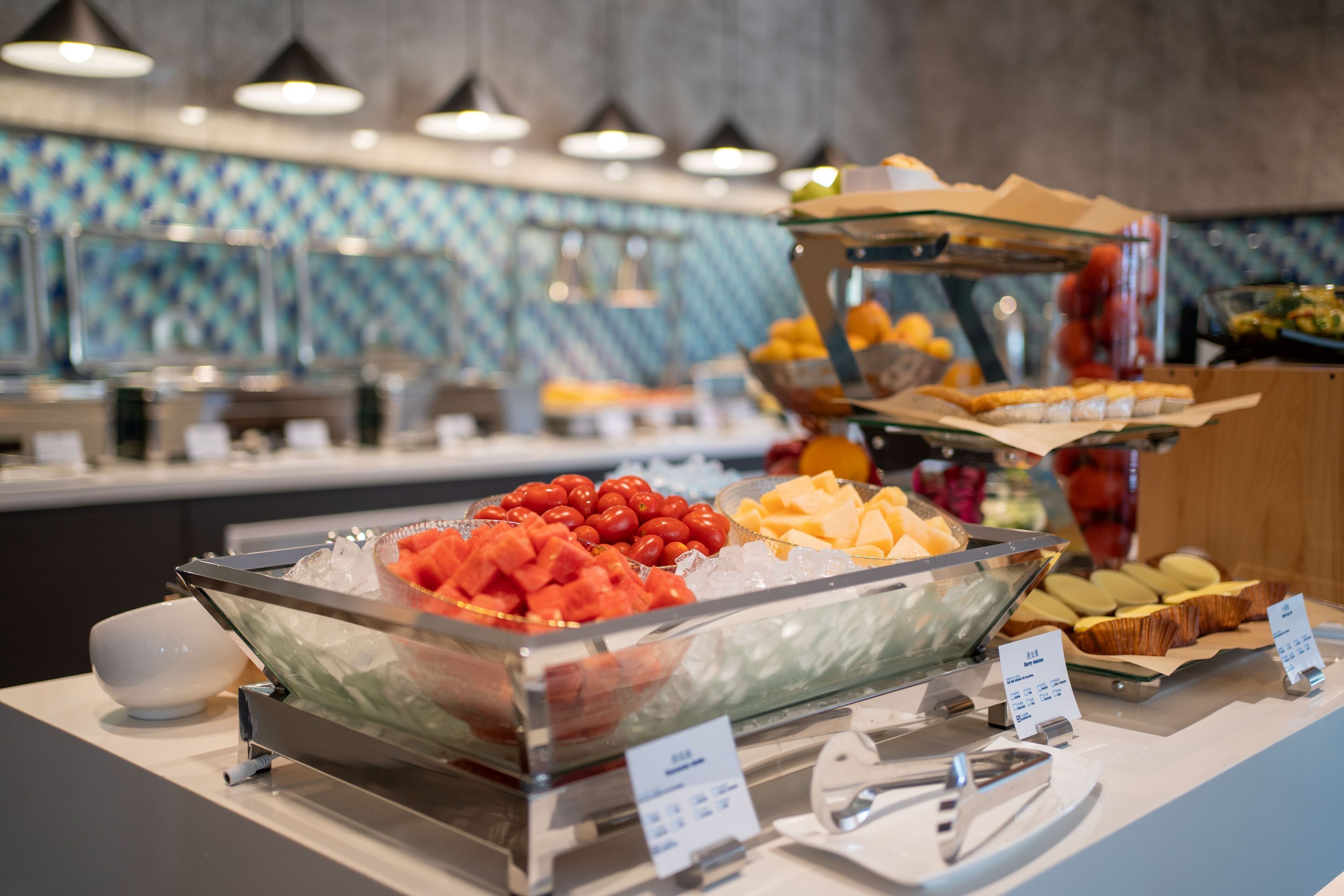 A buffet with various food items including fruits, cheeses, and pastries.