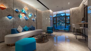 A modern lobby with a curved white sofa, blue armchairs, a coffee table, and a bar area with stools. - Holiday Inn Express Guangzhou Panyu by IHG (Guangzhou)