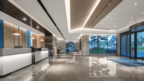 A modern lobby with a reception desk, seating area, and large windows offering a view of the outdoors. - Holiday Inn Express Guangzhou Panyu by IHG (Guangzhou)