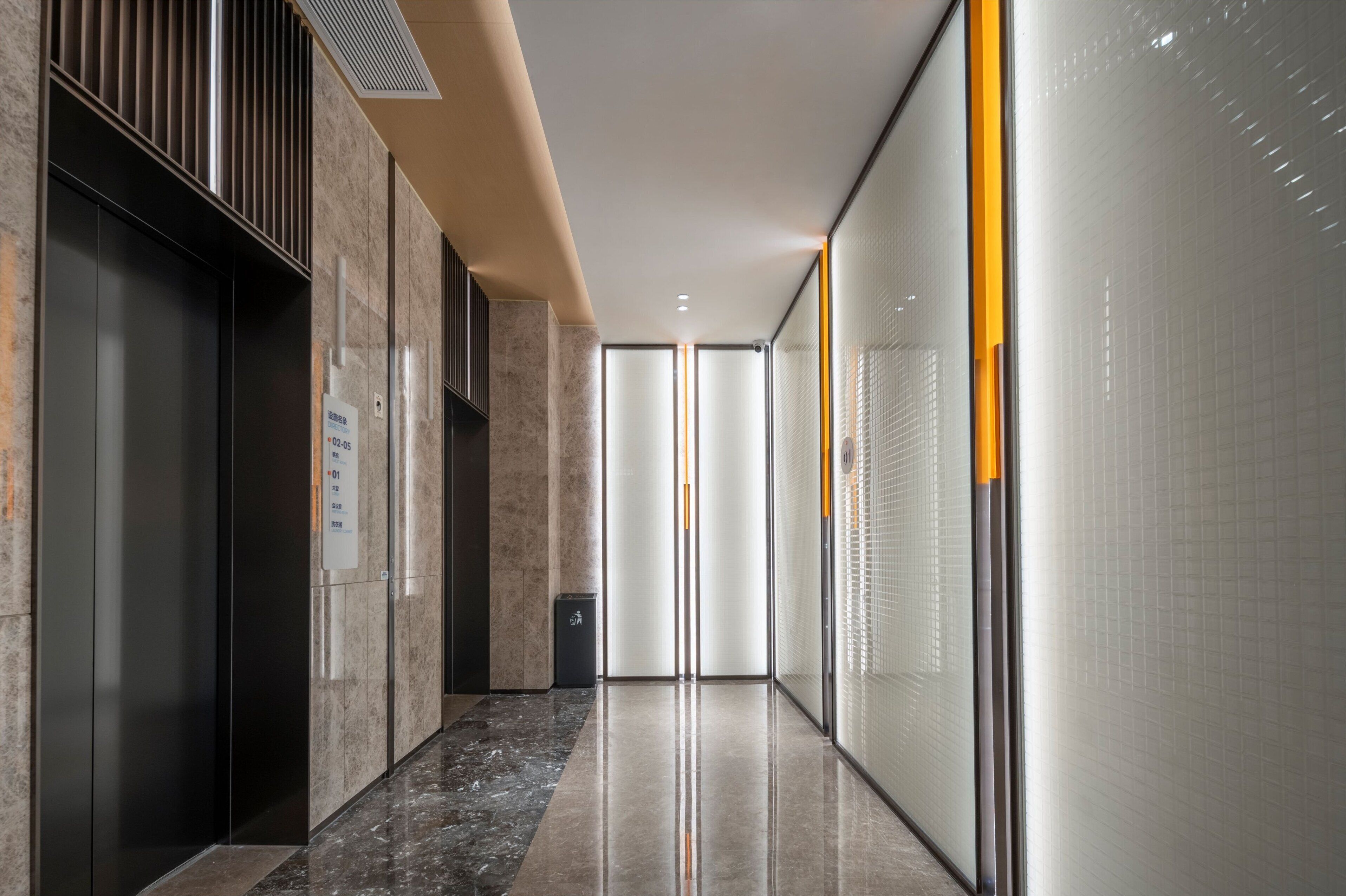 A modern hallway with a marble floor, a glass partition, and a door with a sign.