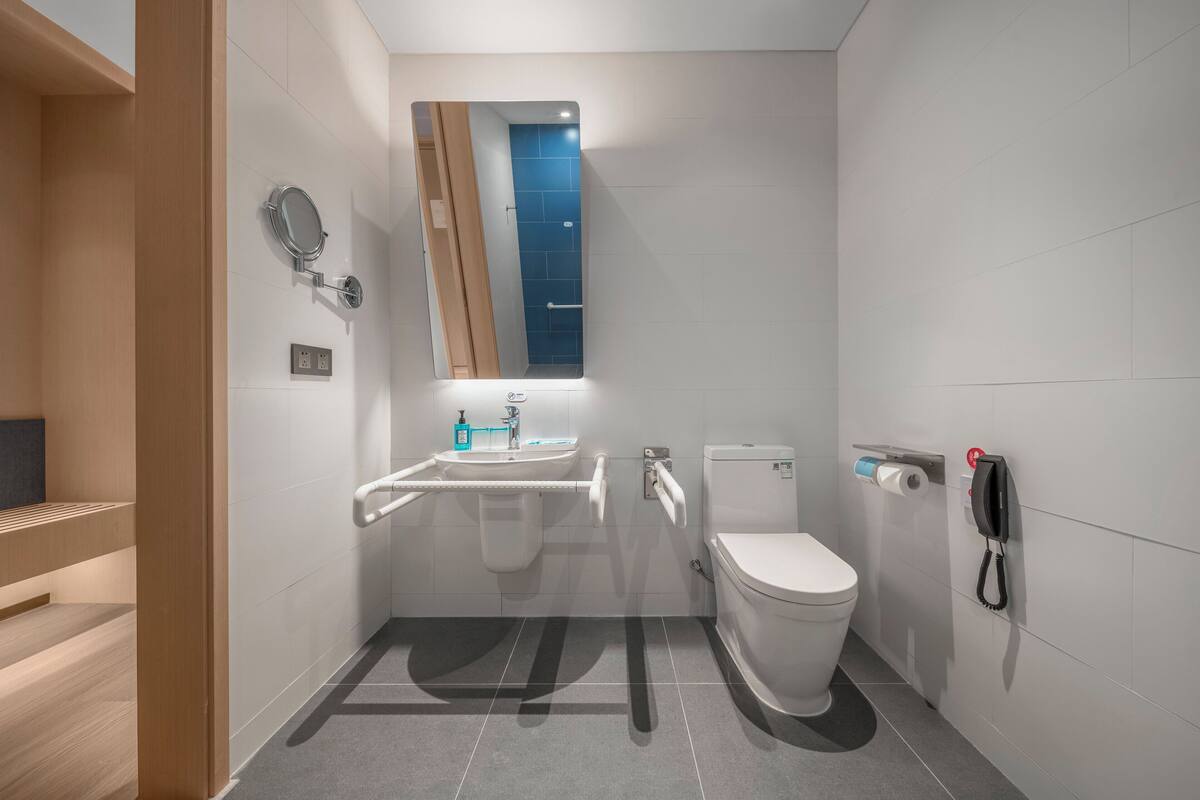 A modern bathroom with a toilet, sink, and mirror.