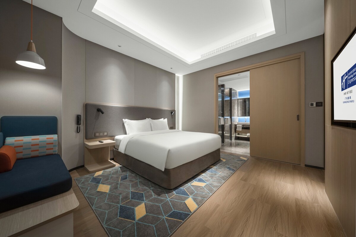 Een moderne hotelkamer met een groot bed, een bureau, een stoel en een bank.