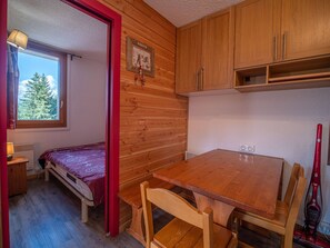 Pieni huone, jossa on puinen pöytä, sänky ja ikkuna, josta avautuu näkymä puuhun.