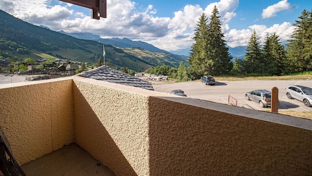 Varanda com vista para um parque de estacionamento e montanhas.