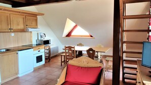 Cocina compacta con comedor, cama en literas y una ventana pequeña.