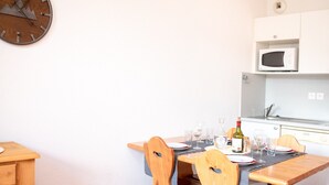 Een eetgedeelte met een houten tafel, stoelen en een klok aan de muur.