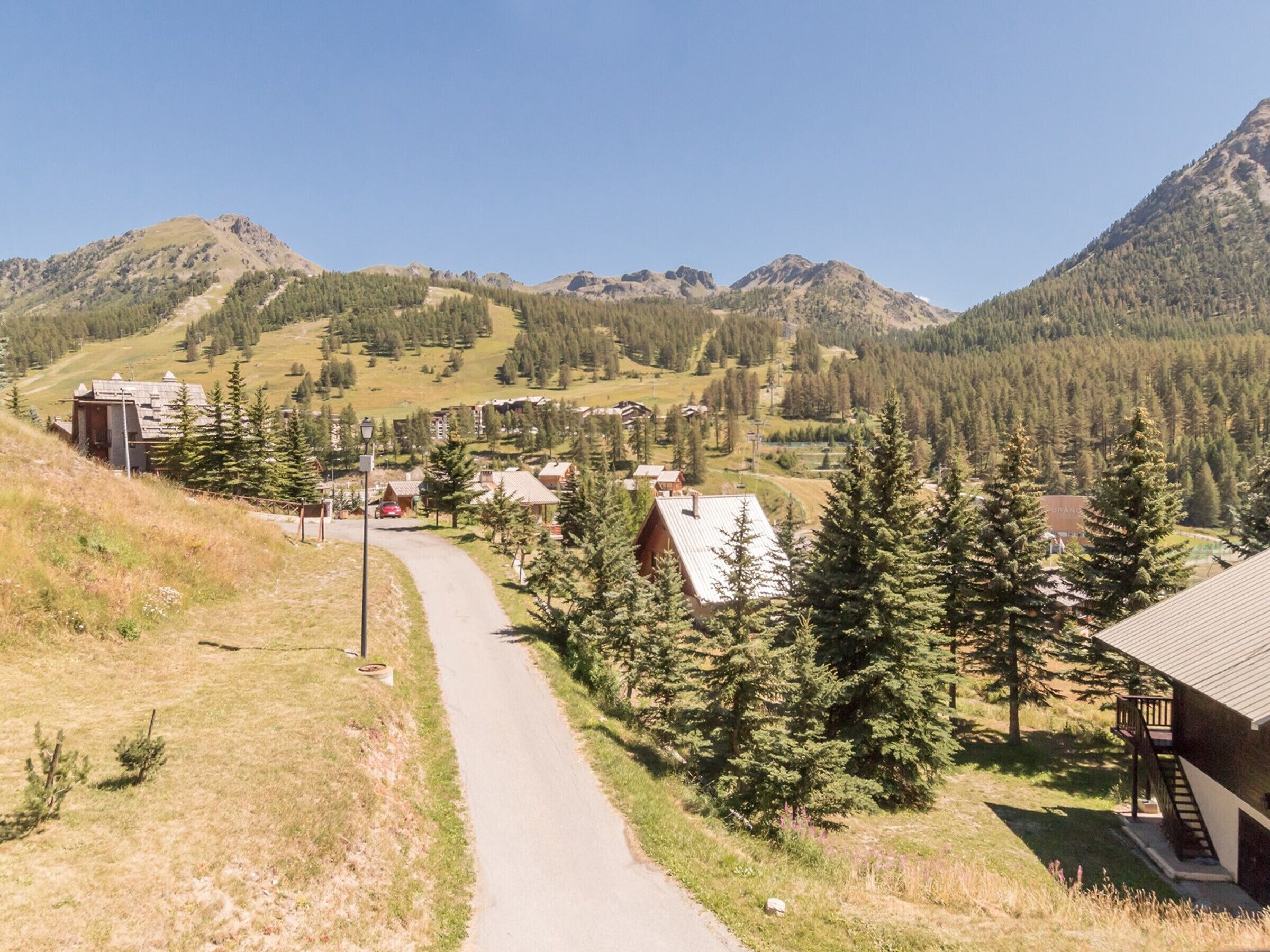 A mountain road leading to a small village with houses and a restaurant.